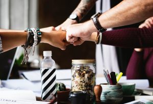Friends, colleagues, inner circle, team giving each other fist bumps.